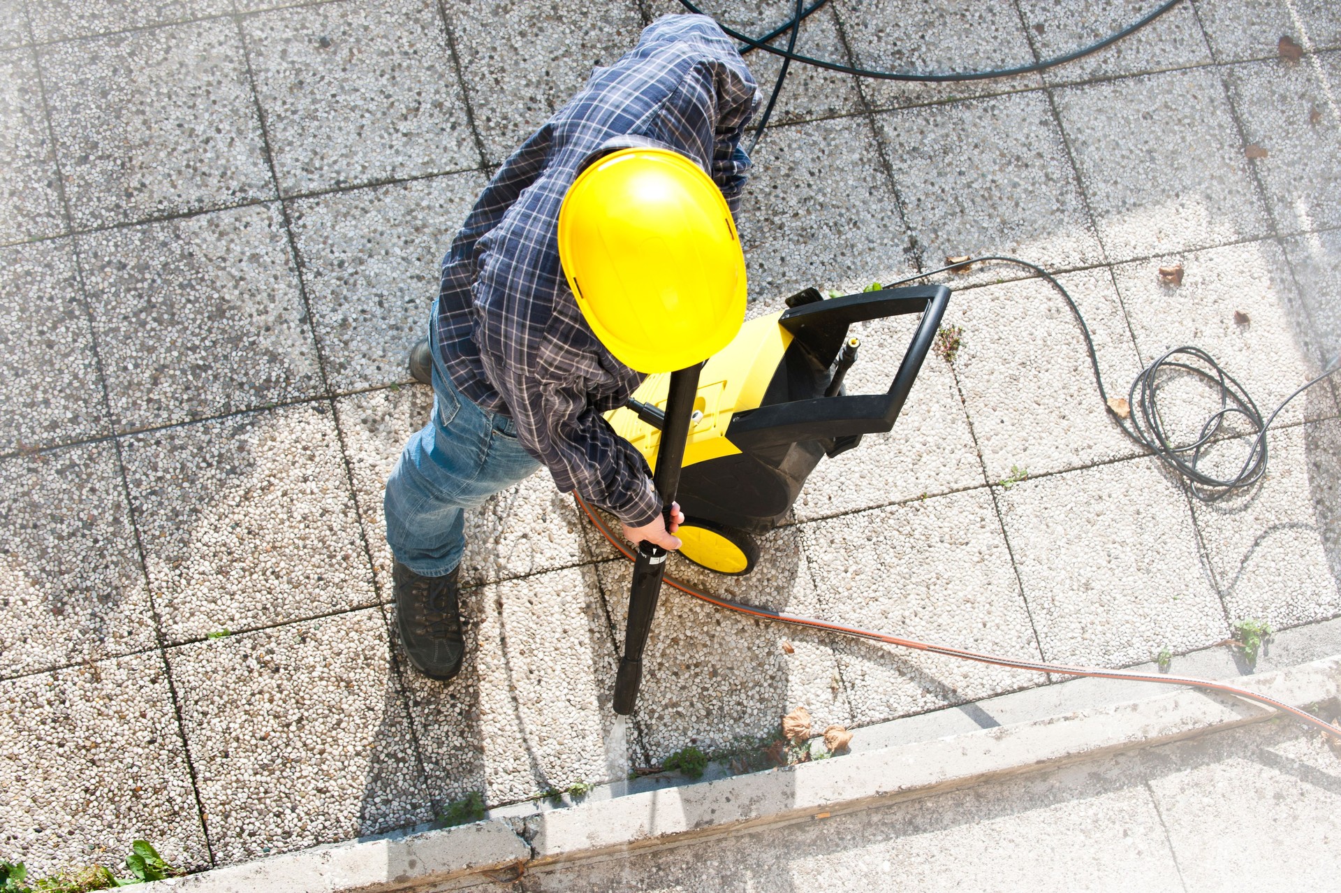 Worker using a pressure cleaner on a sidewalk